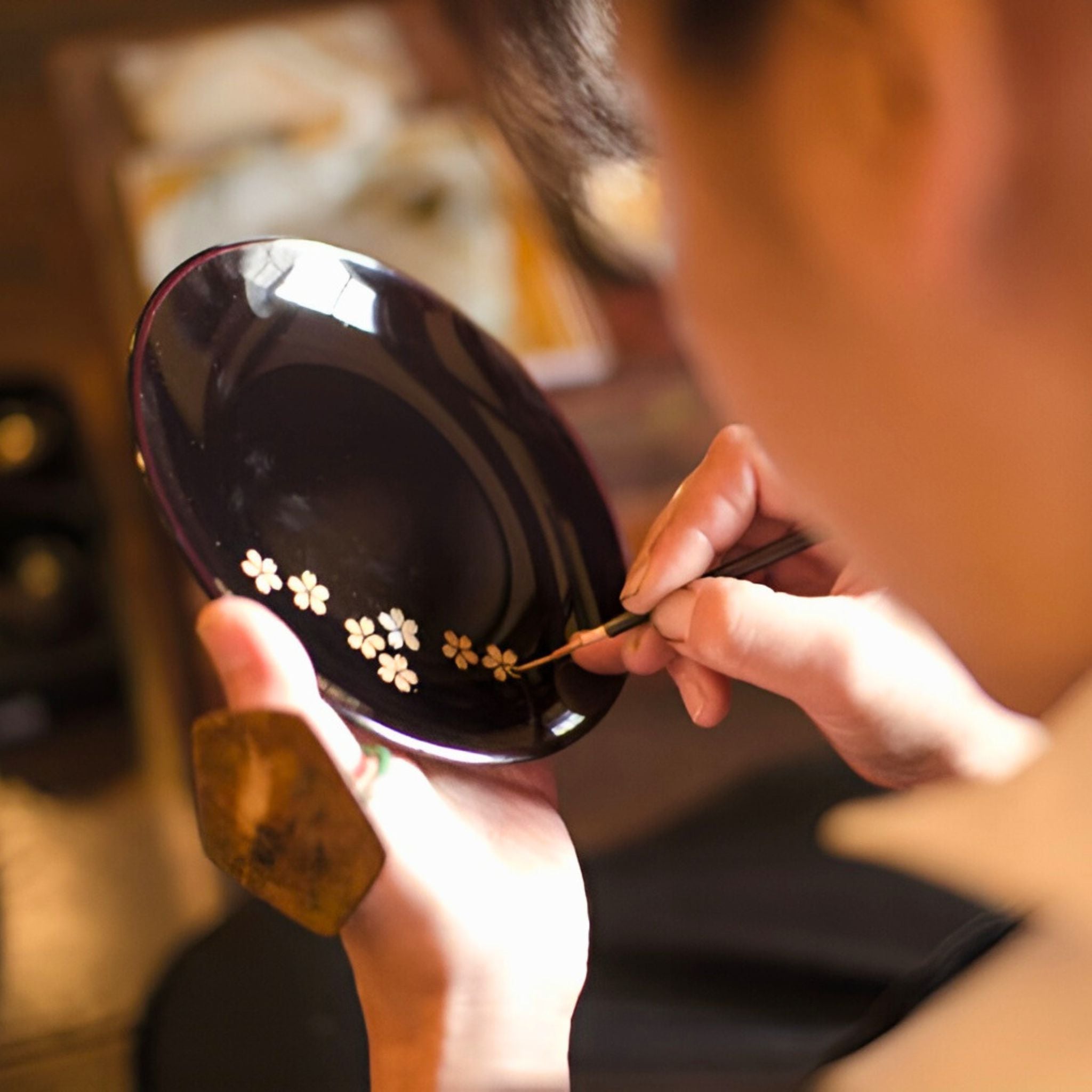 Artisan painting sakura on the lacquerware plate