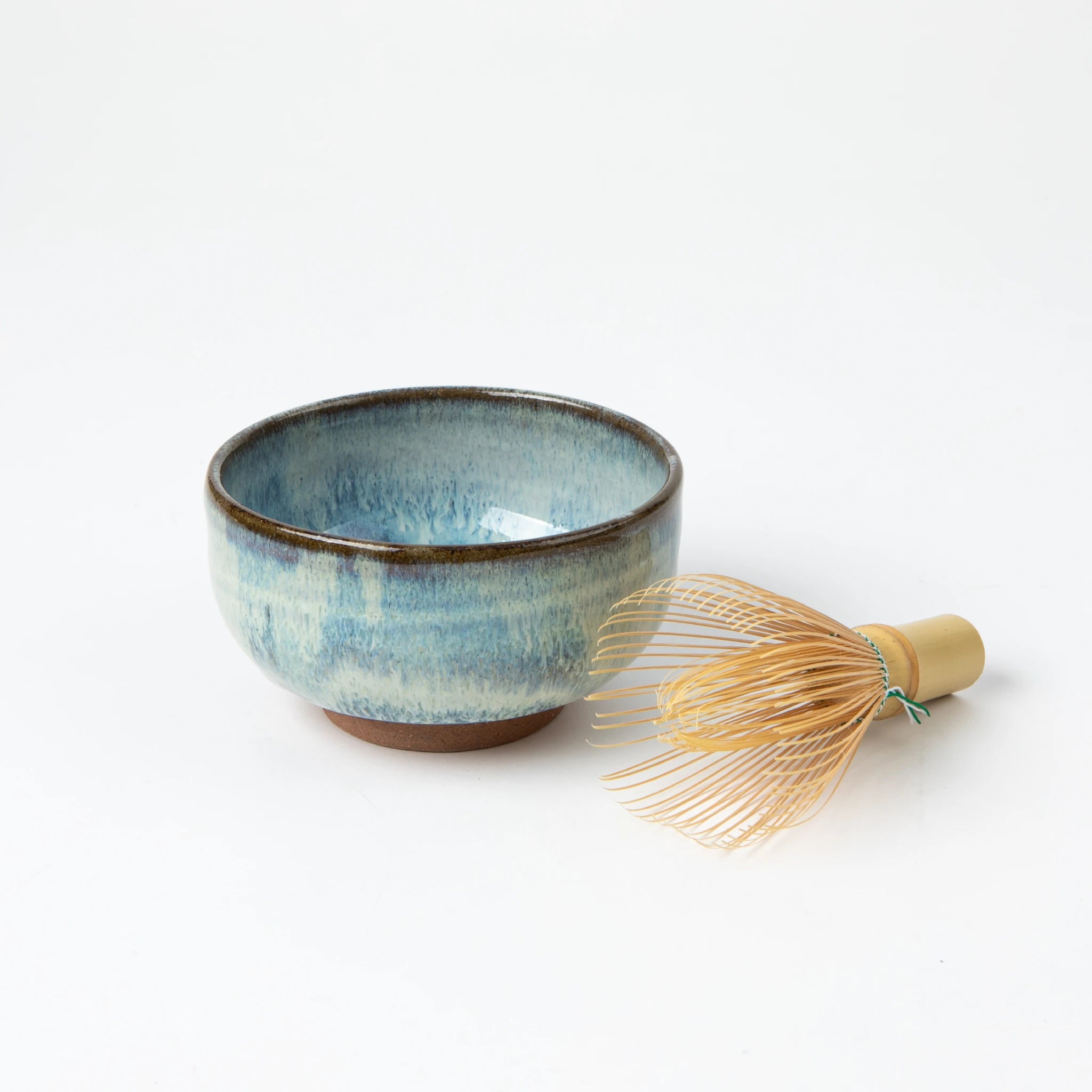 The Blue Shodai matcha bowl next to a bamboo chasen whisk, styled for a traditional tea preparation setting.