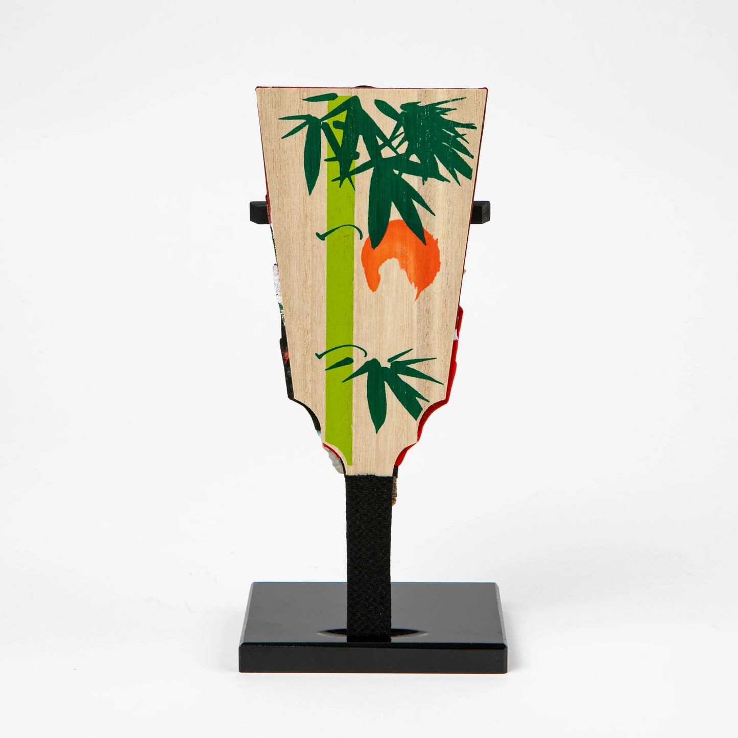 The reverse side of the hagoita paddle, hand-painted with green bamboo leaves and a red-orange motif on natural wood grain.