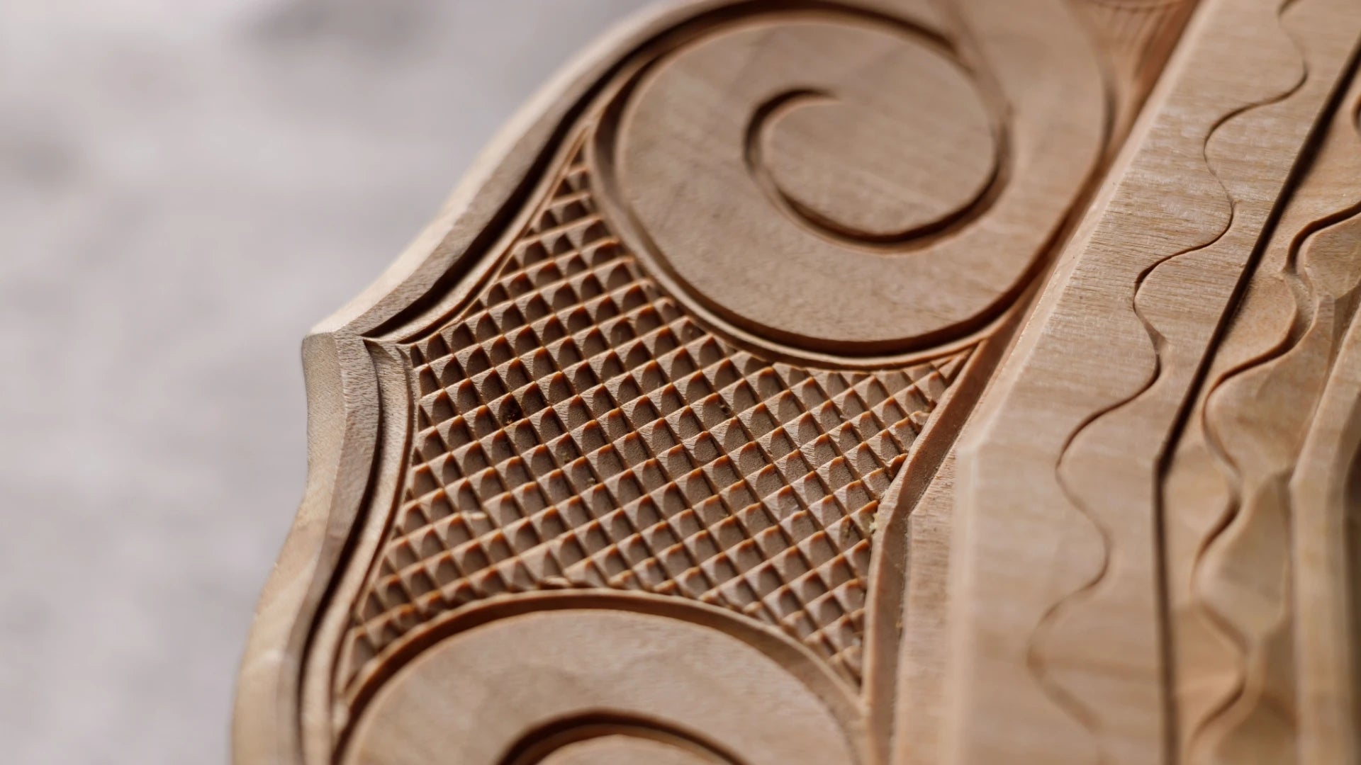 Close-up of Ainu wooden carvings with intricate patterns on a light background