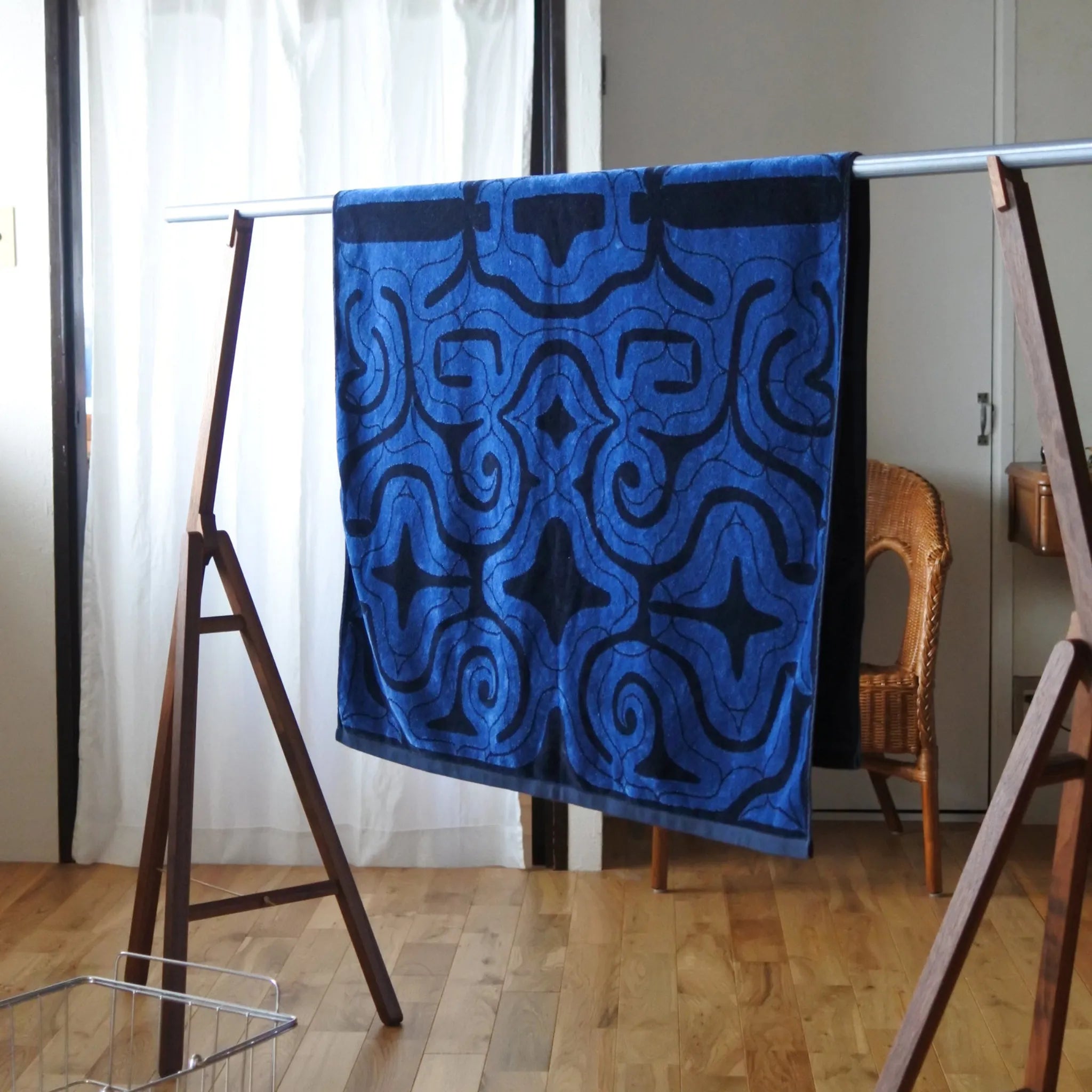 Blue Ainu patterned towel hanging on a rack indoors