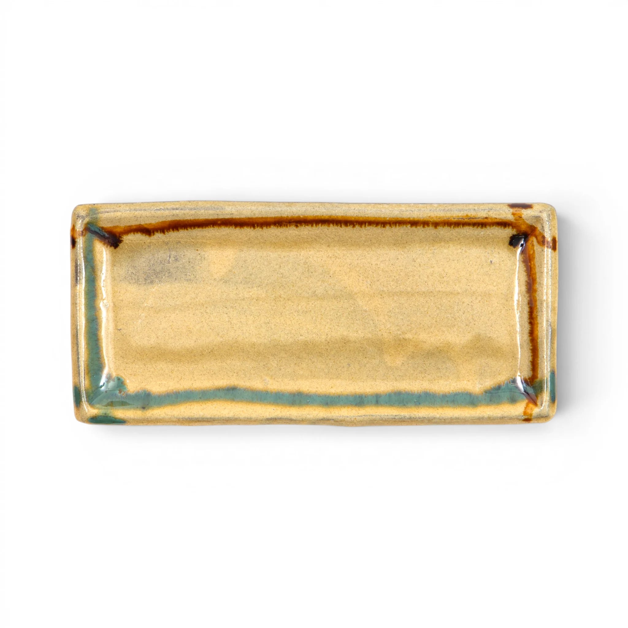 Top view of a Ryumonji Yaki rectangular pottery plate showing an amber sansai glaze field with teal accumulation along the rim and dark iron runs at the corners and edges.