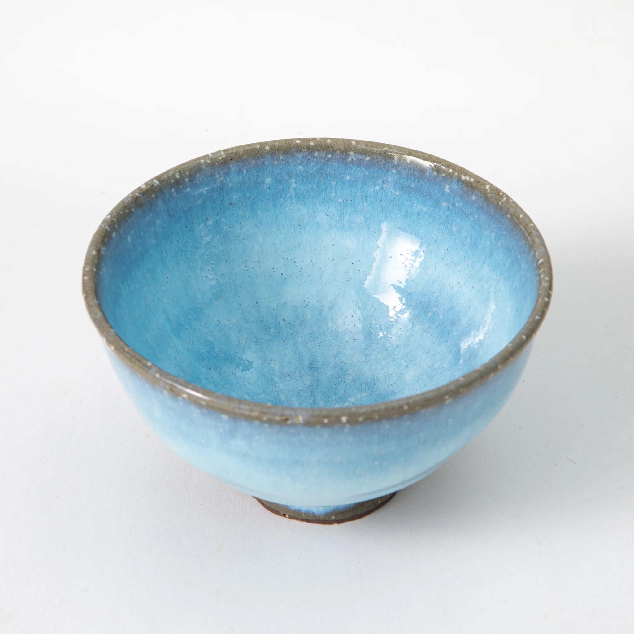 A Hagi ware matcha bowl by Senryuzan photographed from above, showing the full interior in soft sky blue glaze with white mineral speckles and a warm grey textured rim.