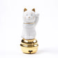 A white porcelain Maneki Neko figurine from Choemon Kiln, sitting atop a gold bell. The cat has gold accents on its ears and facial features, with a raised left paw.