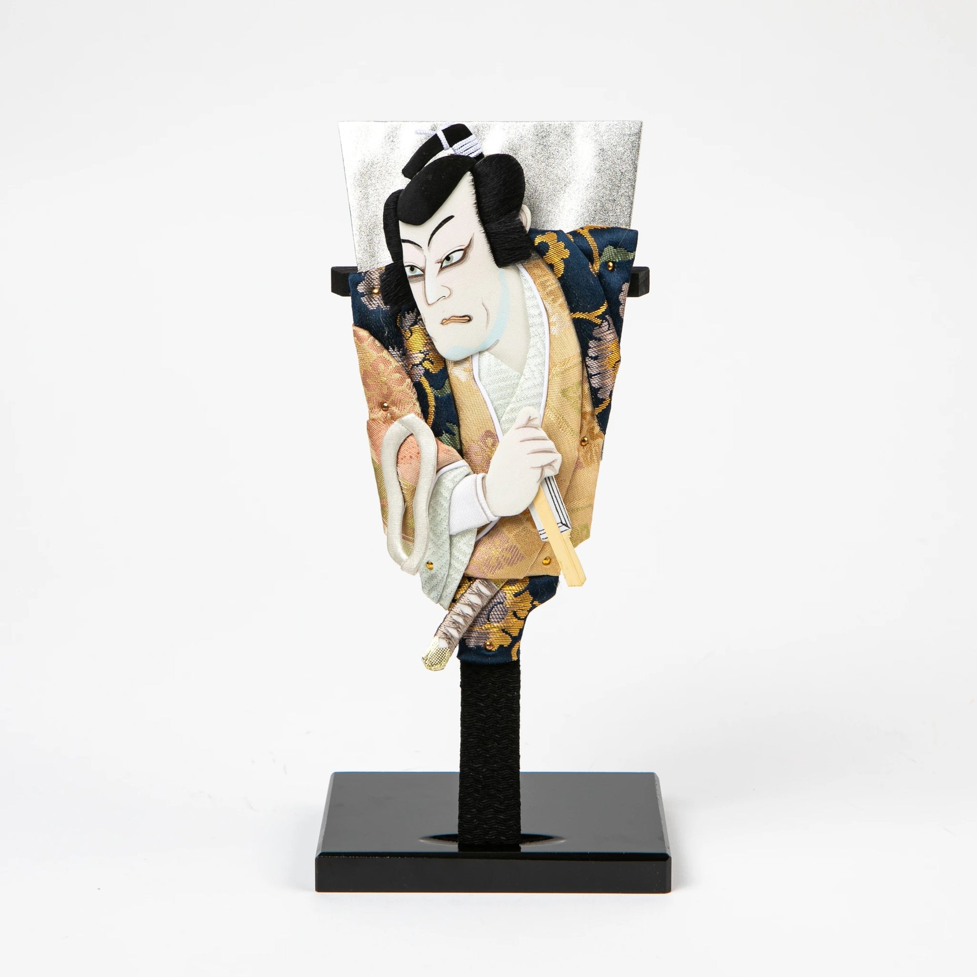 A traditional Japanese hagoita paddle featuring a male kabuki actor in a gold and navy brocade kimono, gripping a short sword.