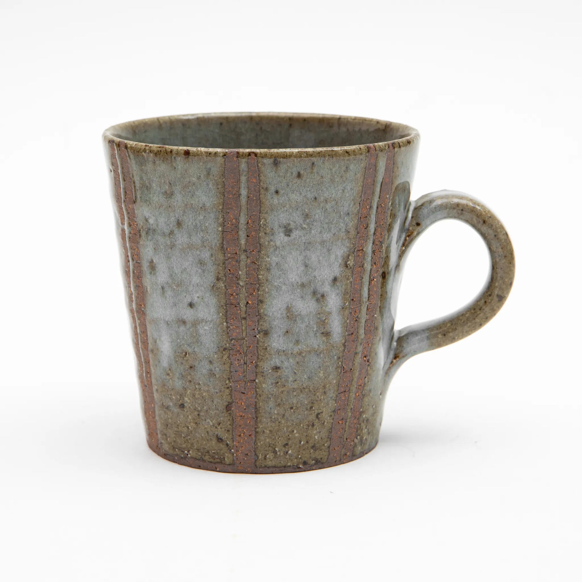 A large Shigaraki ware mug by Hinomigama, featuring a muted grey glaze over a coarse, speckled clay body with vertical incised terracotta lines and a hand formed loop handle, set against a white background.