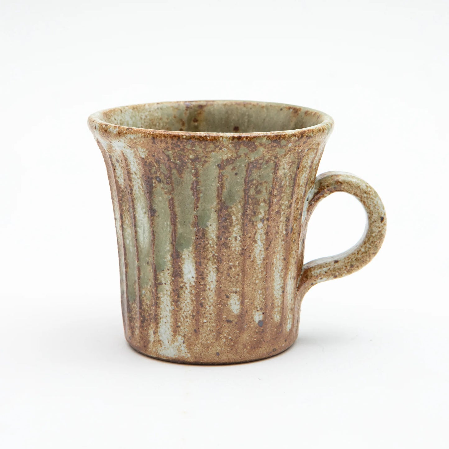A Shigaraki ware mug by Hinomigama with vertical ribbed grooves, a kohiki white slip base and vidro ash glaze in soft sage and celadon tones over a warm iron rich clay body, set against a white background.