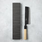 Ishizuchi Blue Steel No.2 Nakiri Knife with magnolia handle displayed next to a minimalist black box, emphasizing traditional Japanese elegance.