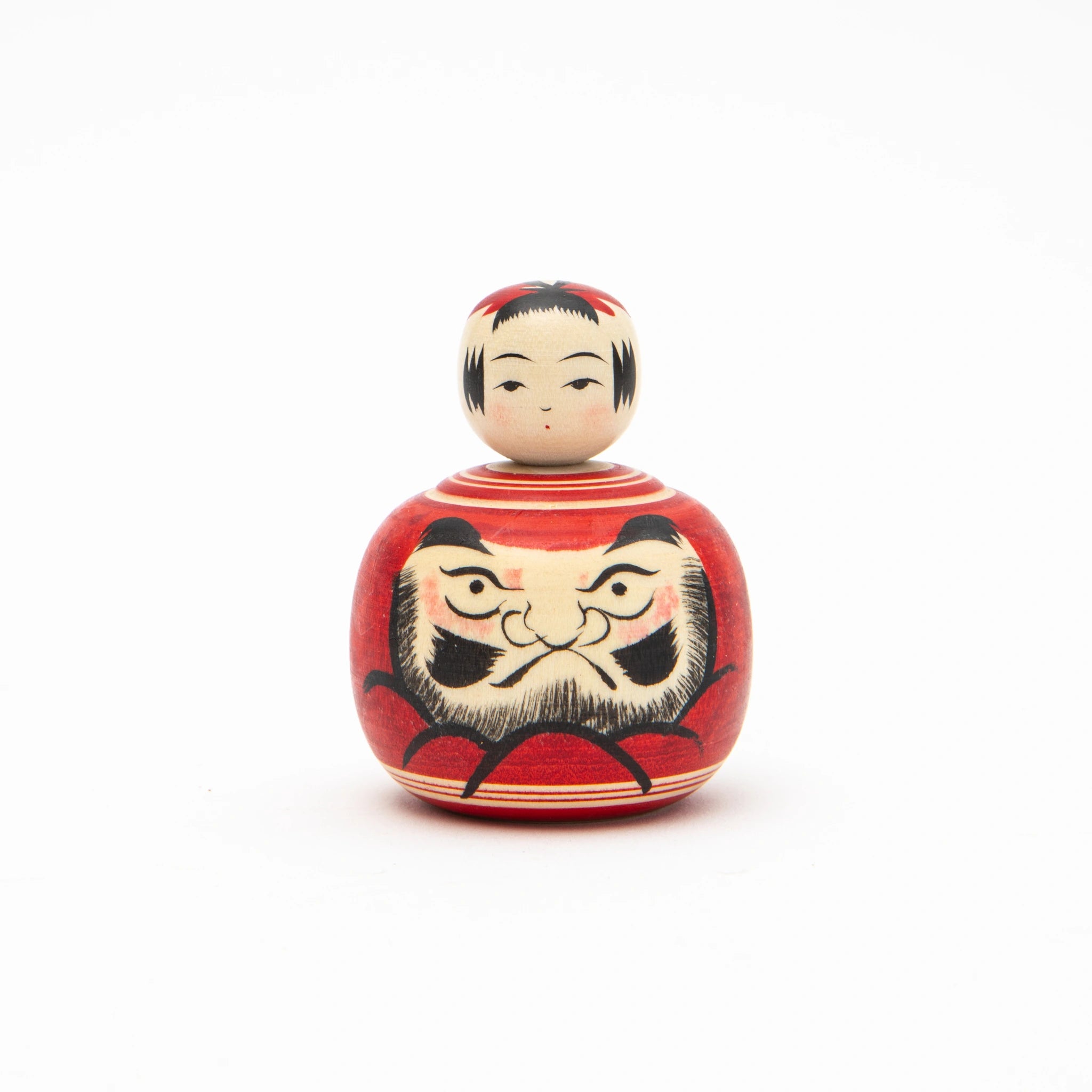 Front view of a 4.5cm Daruma Ejiko kokeshi doll by Kakizawa Kokeshi Studio, showing a low rounded body painted in red with a hand-painted Daruma face featuring bold brows, resolute eyes, and white beard, topped with a small rounded head with black fringe detail.