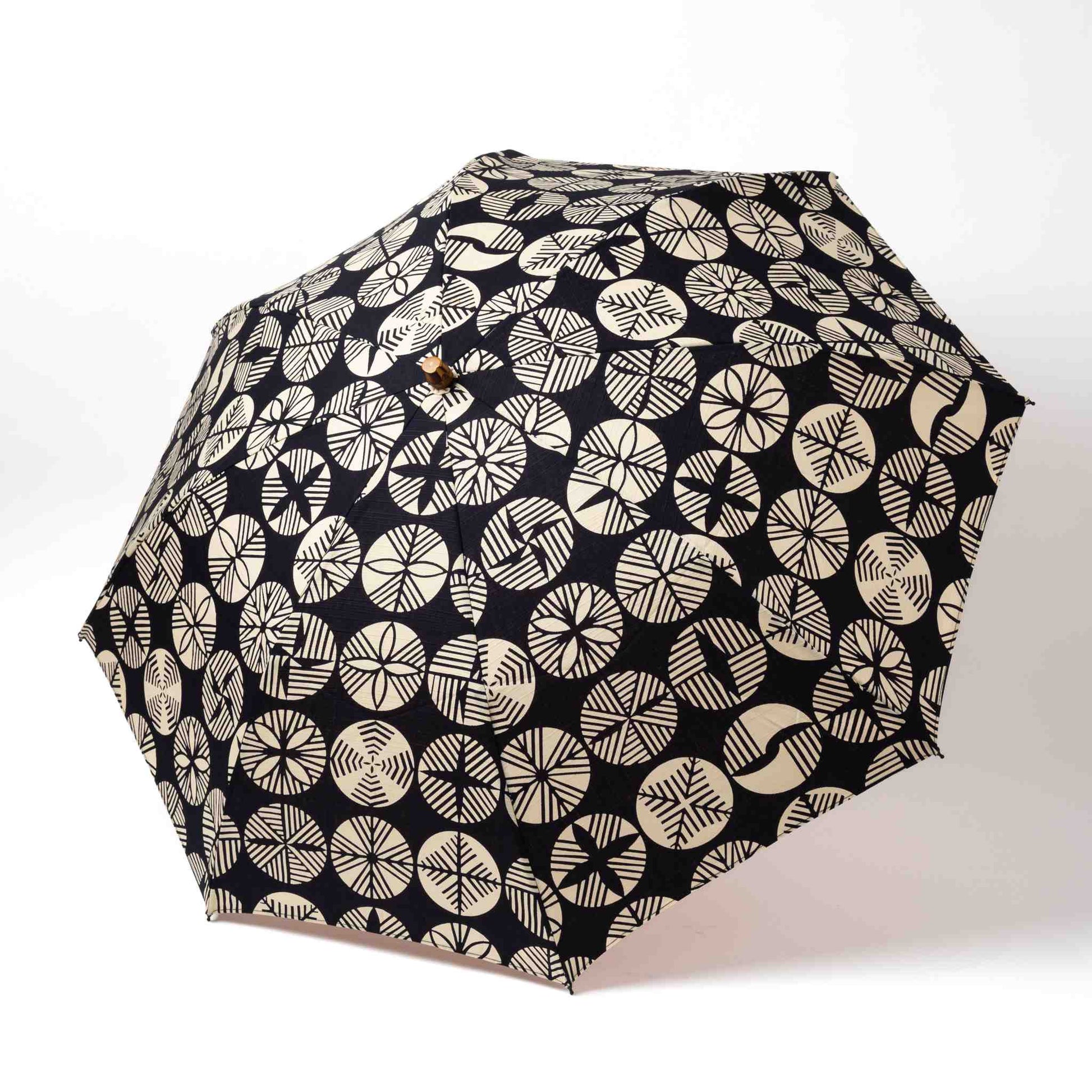 Isa Moyō Folding Umbrella fully opened, showcasing the intricate Pine Tree motif against a dark navy  background.