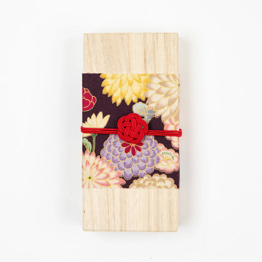 A wooden box wrapped with floral fabric and a red decorative knot, used for packaging traditional Japanese incense.
