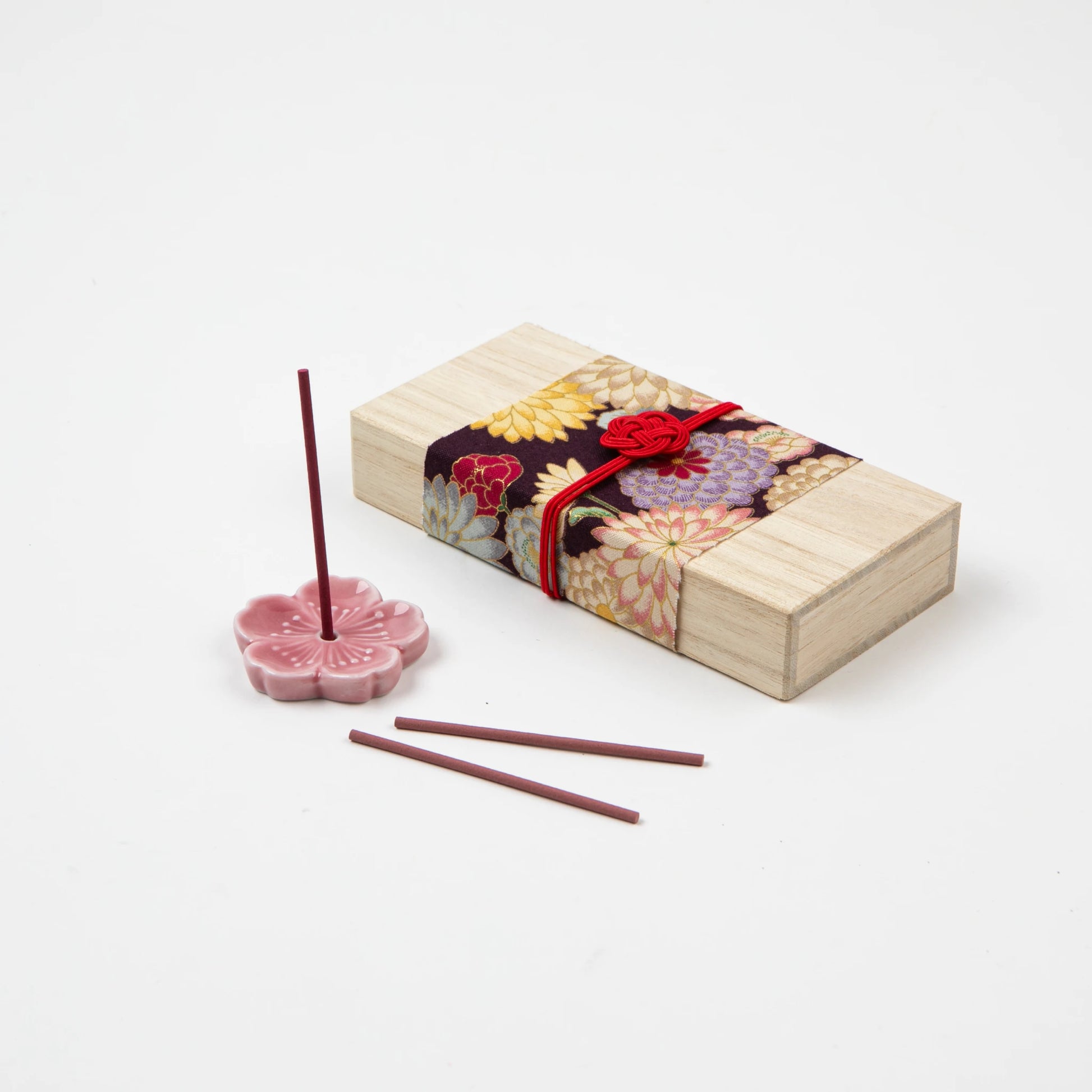 Sakura-themed incense set with a lit incense stick in a cherry blossom holder and decorative box in the background.