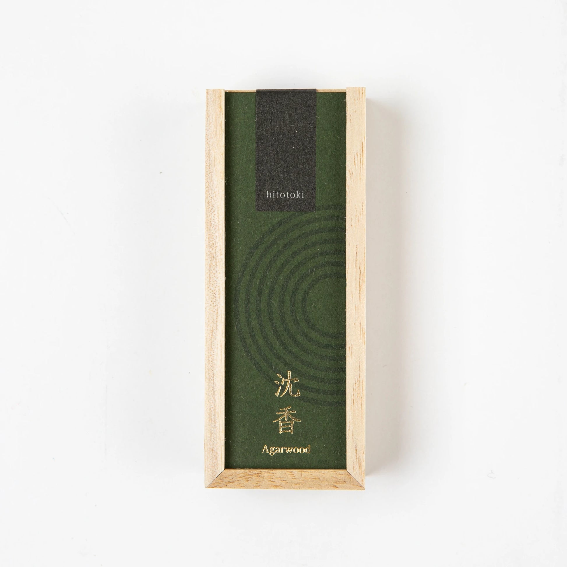A top-down view of a rectangular wooden box with a green label reading "hitotoki Agarwood" in English and Japanese.