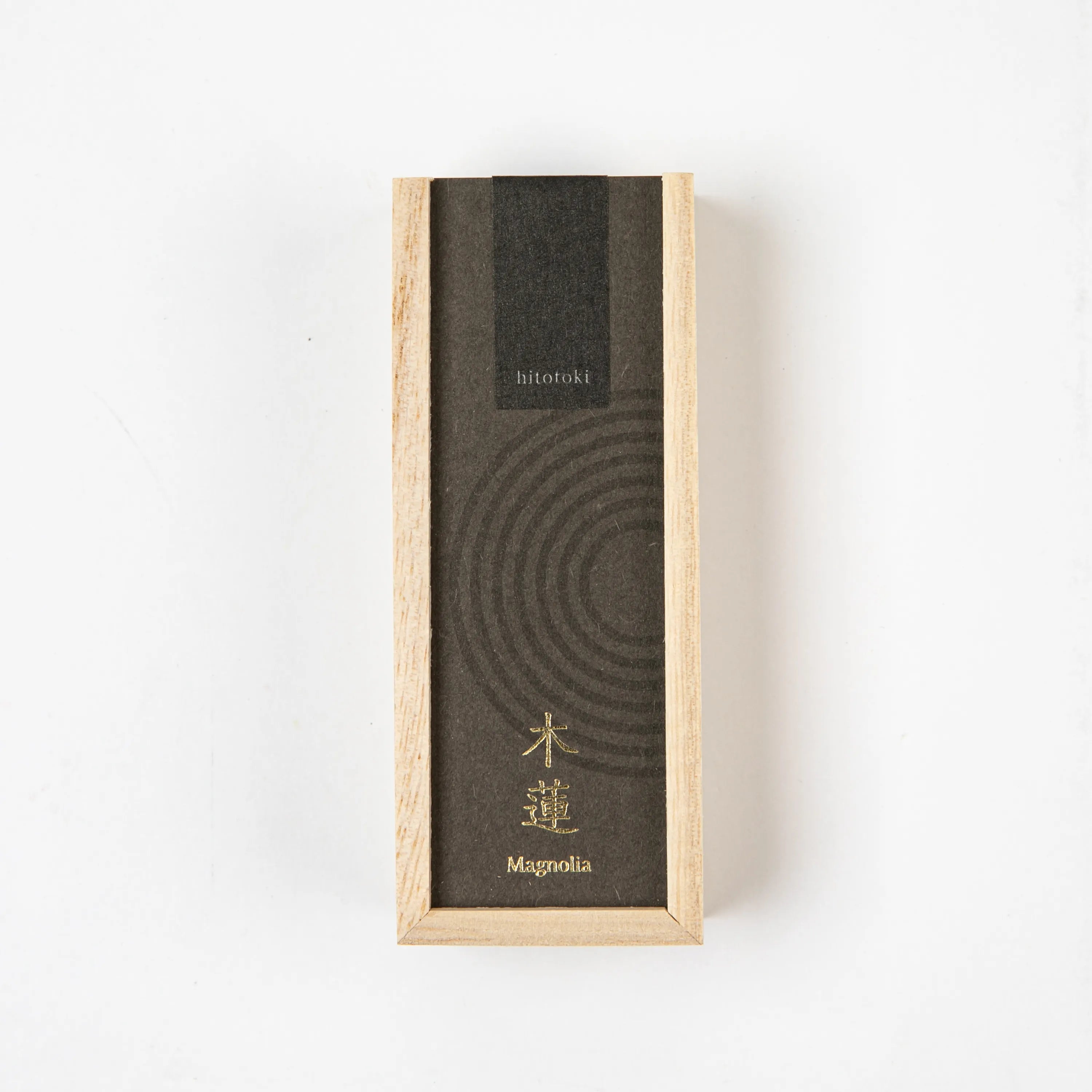 A close-up of the hitotoki Magnolia incense box, featuring dark packaging with subtle circular patterns and gold lettering.