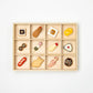 Set of 12 ceramic chopstick rests shaped like Japanese foods, neatly arranged in a wooden box with compartments.