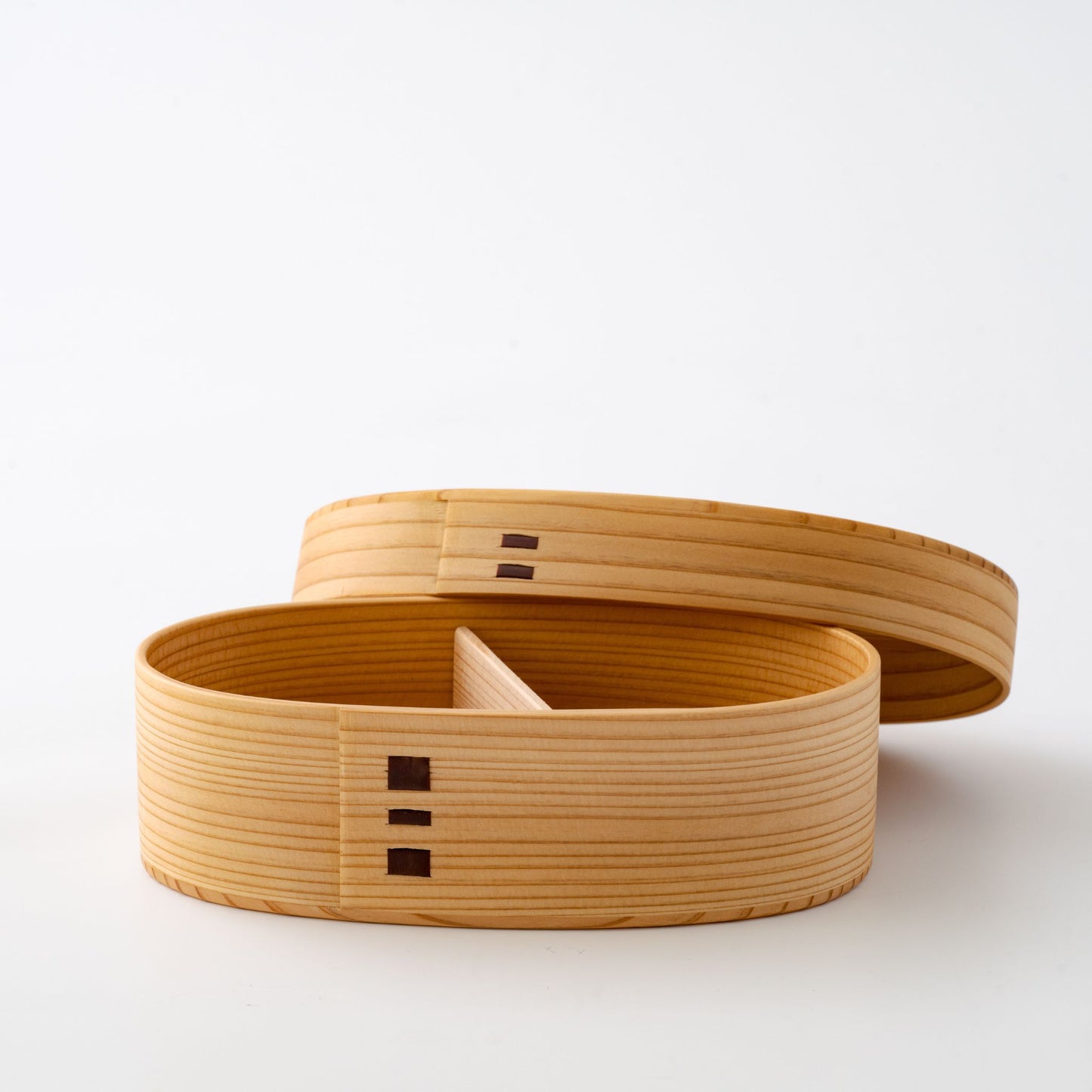A two-tiered wooden bento box with one tier open, showing the divided compartments inside.