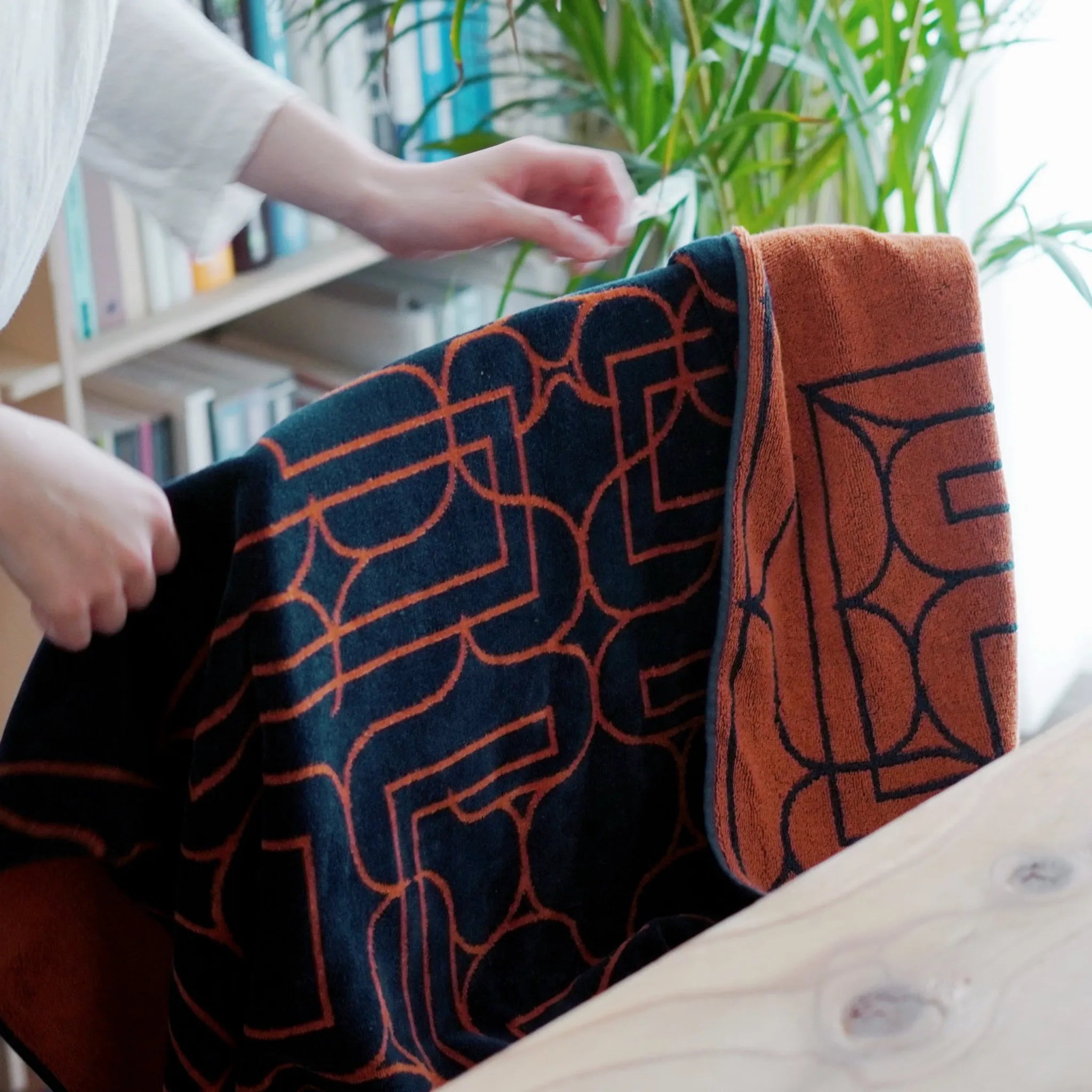 Person holding Ainu patterned fabric with geometric design in a home setting