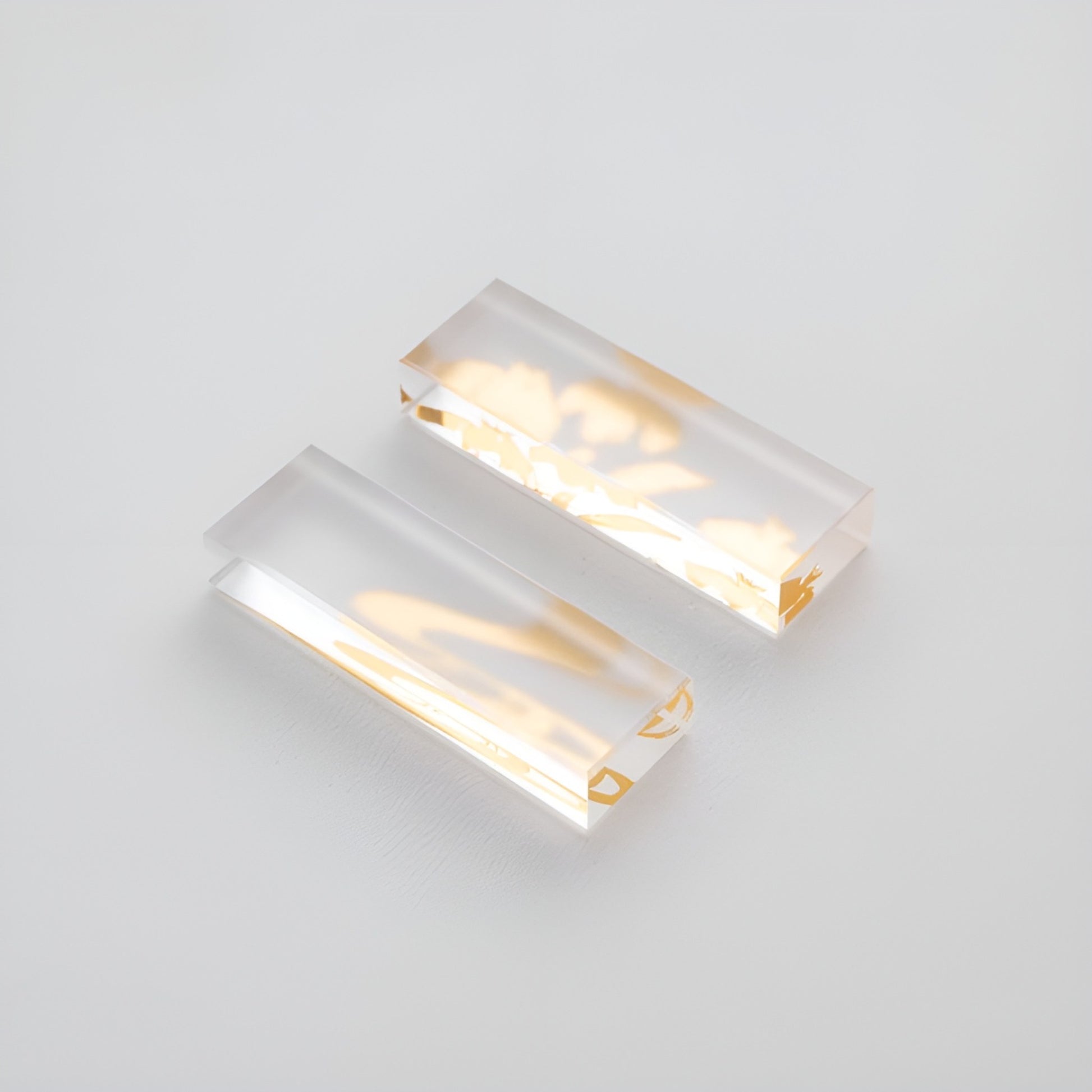 Close-up of two transparent chopstick rests with golden decorative patterns embedded inside, offering an elegant and refined touch.