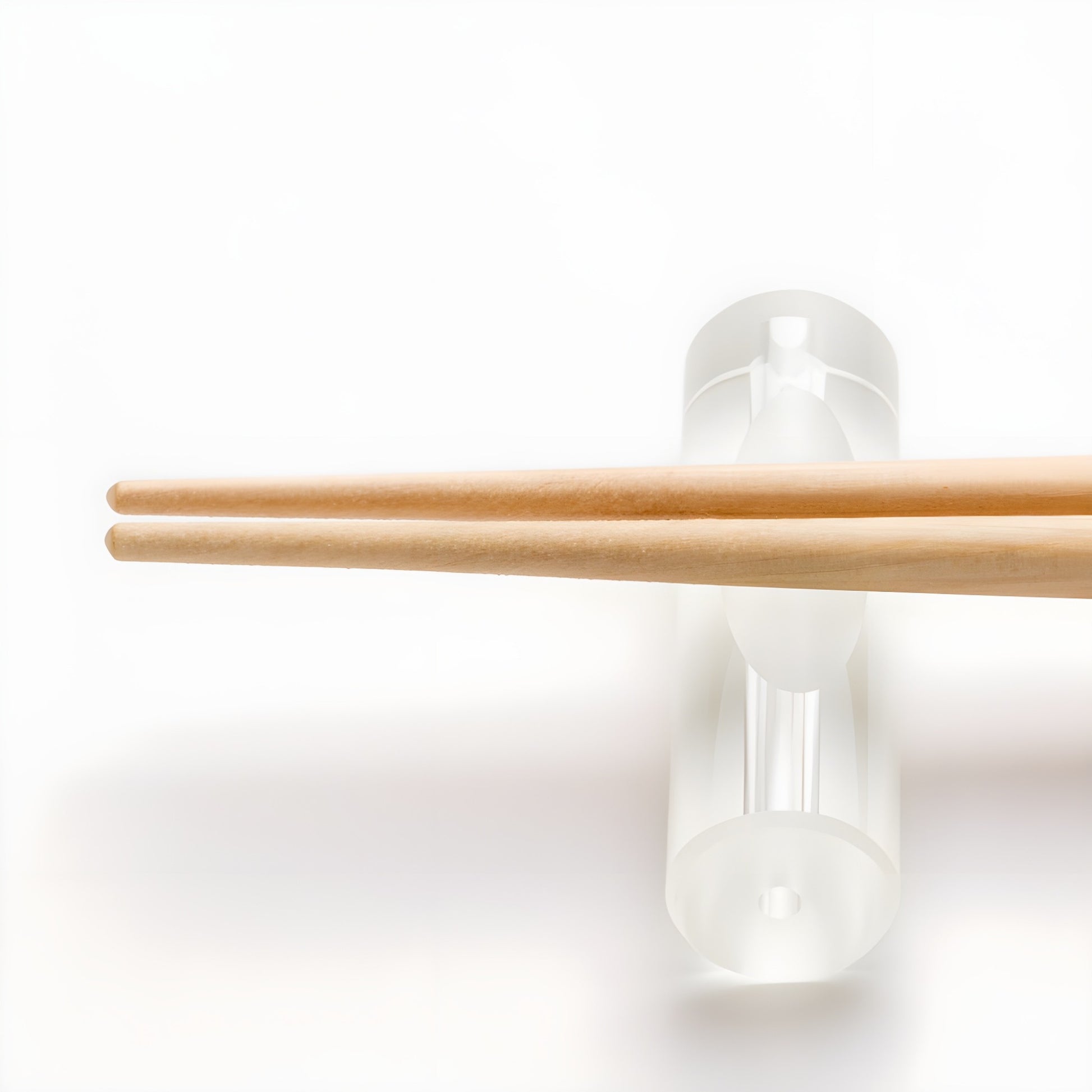 Natural wood chopsticks resting on a clear acrylic chopstick rest, showcasing the smooth tips and minimalistic design of the set.