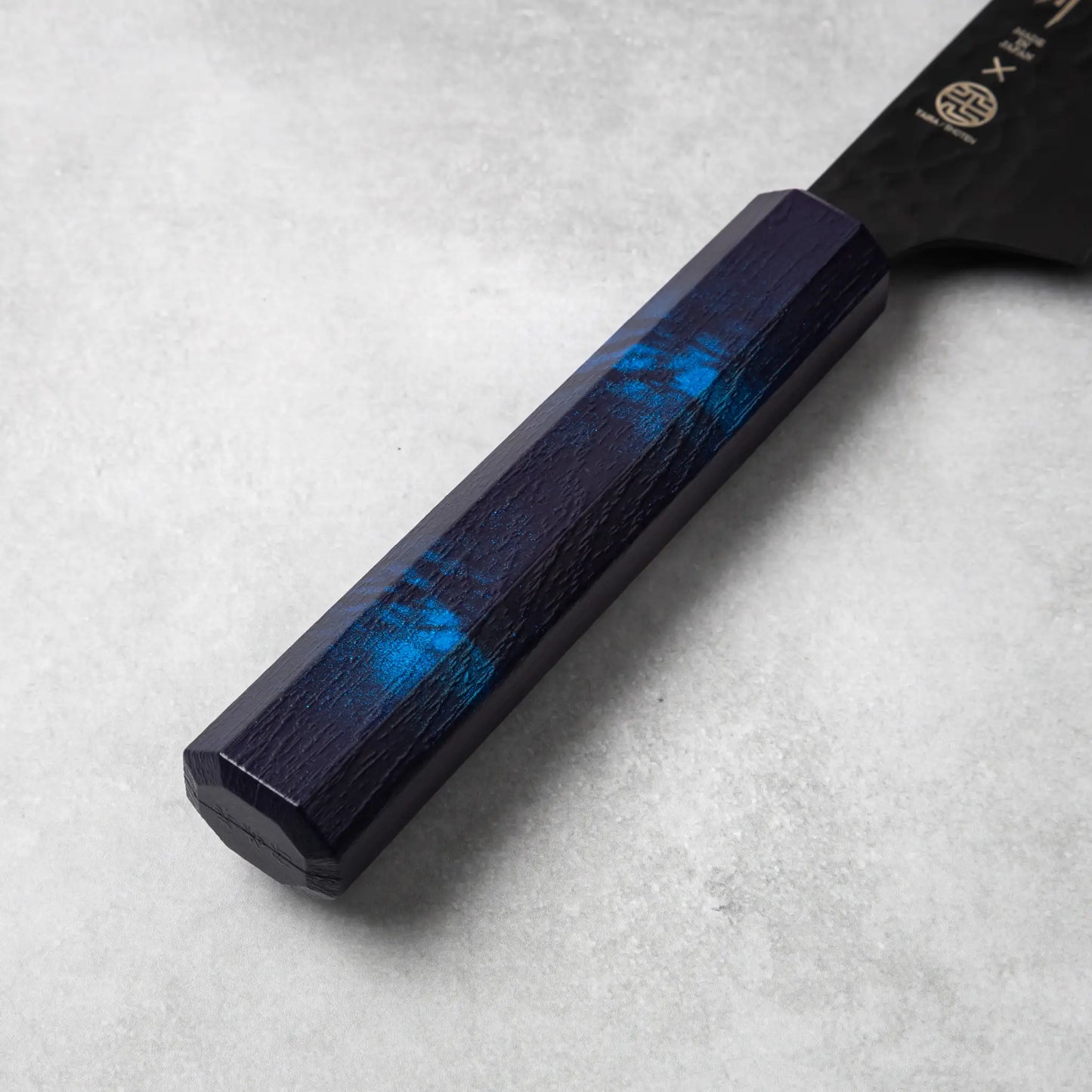 A focused shot of the blue octagonal handle of the Sakai Takayuki Kurokage VG10 Kengata Santoku Knife, highlighting its textured pattern and ergonomic design