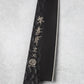 Close-up of the blade engraving on the Sakai Takayuki Kurokage VG10 petty knife, featuring Japanese characters and the "Made in Japan" emblem on the hammered black surface.