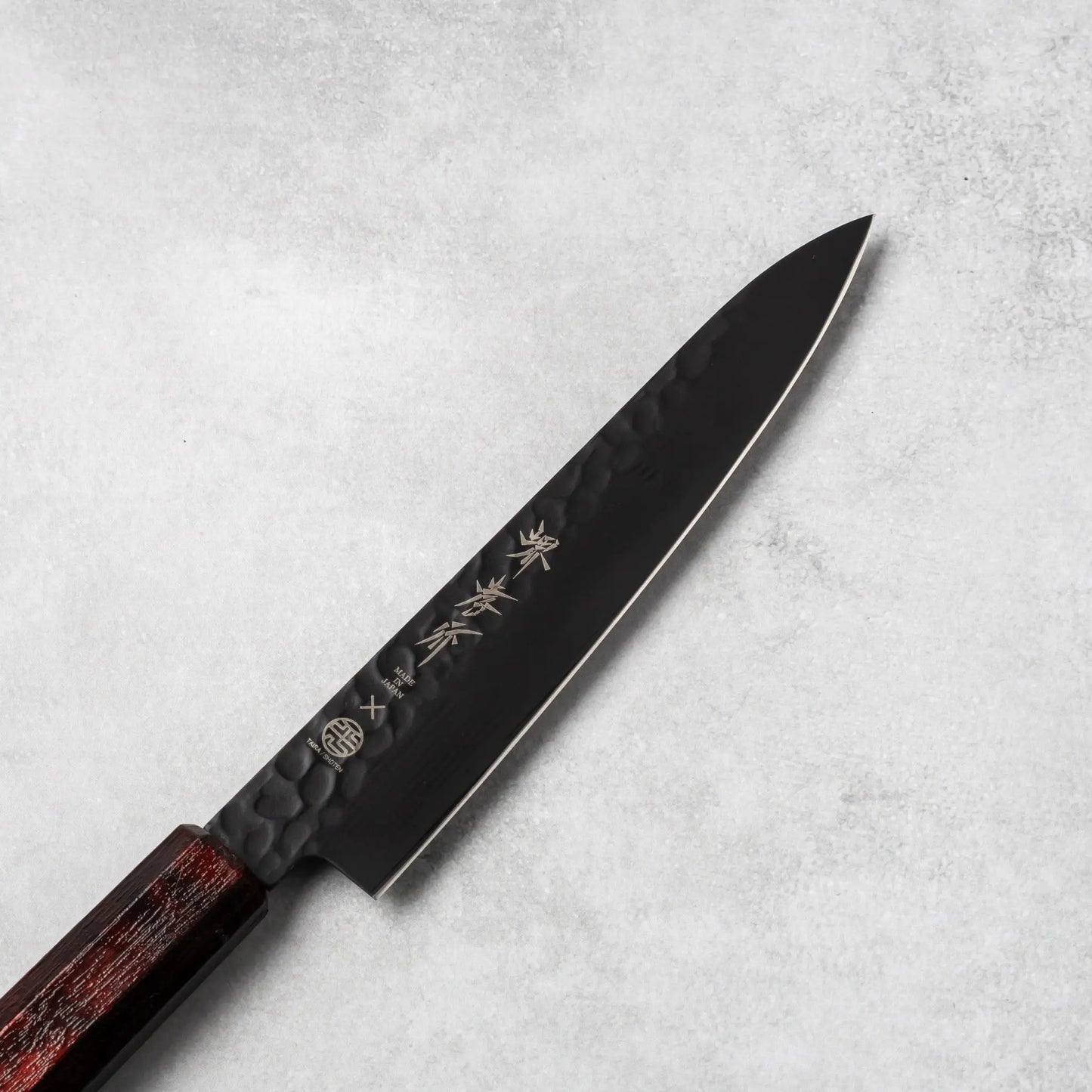 Close-up view of the Sakai Takayuki Kurokage VG10 petty knife's blade, showcasing the hammered texture and engraved Japanese kanji lettering.