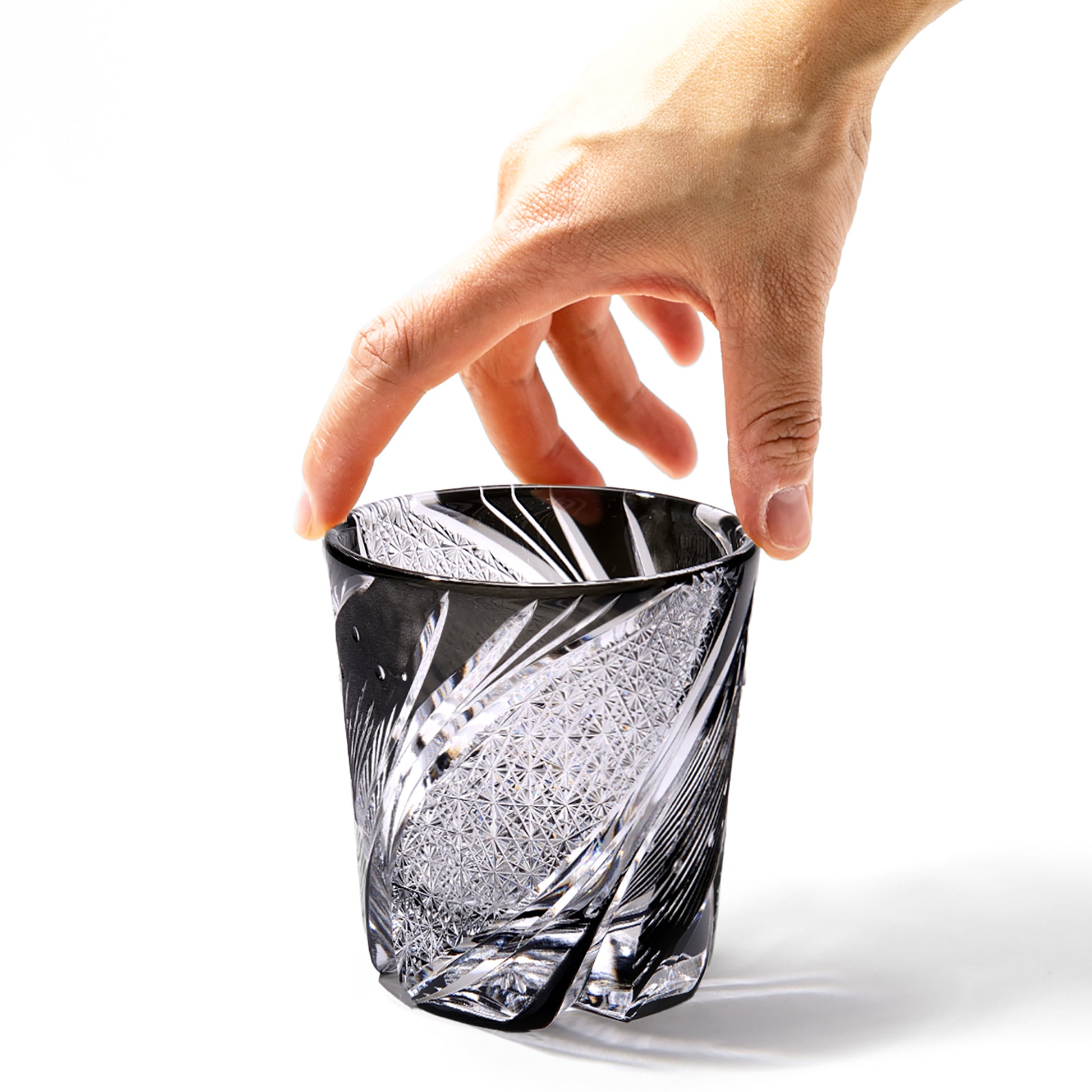 Hand holding black Edo Kiriko Meteor Whiskey Glass from Tableau