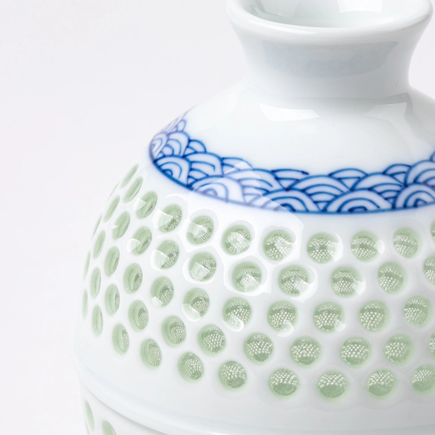 Close-up of the textured celadon glaze and hand-painted wave design on the sake bottle.