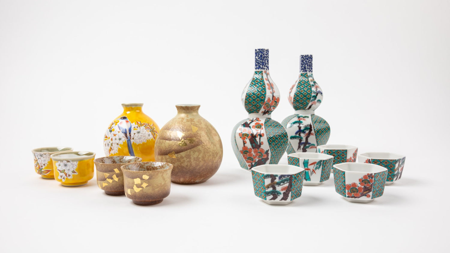 Assorted traditional Japanese sake sets, including vibrant yellow sakazuki cups with floral and bird motifs, earthy brown cups with gold accents, and intricately patterned porcelain bottles and cups featuring geometric and floral designs.